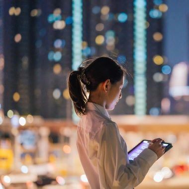 Woman working on a tablet in a city at night